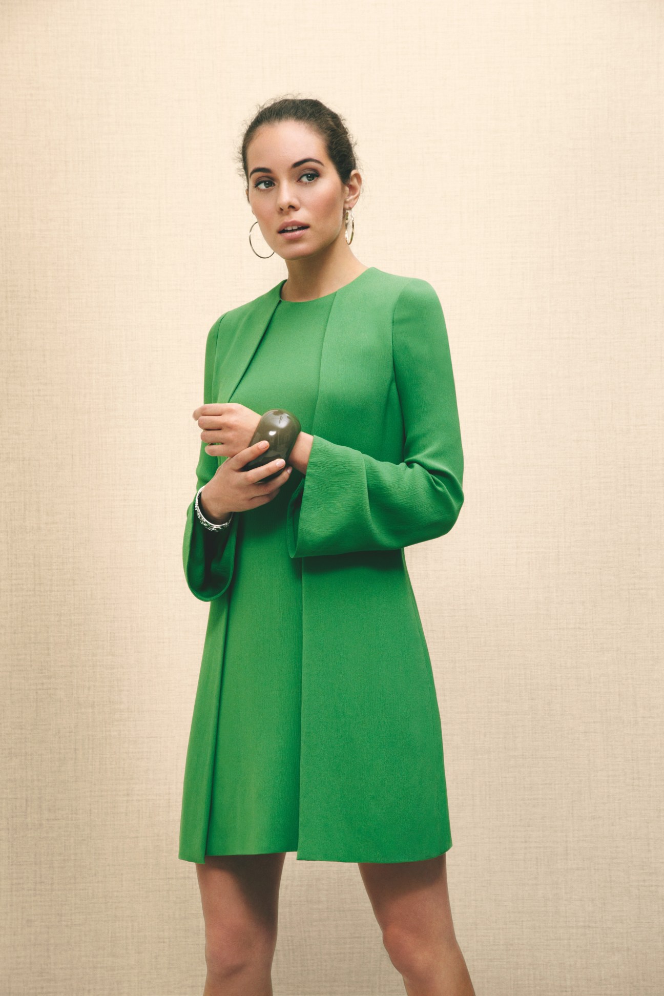 Woman wearing a green Gucci dress with Cartier earrings and Bottega Veneta and Hermès bracelets.