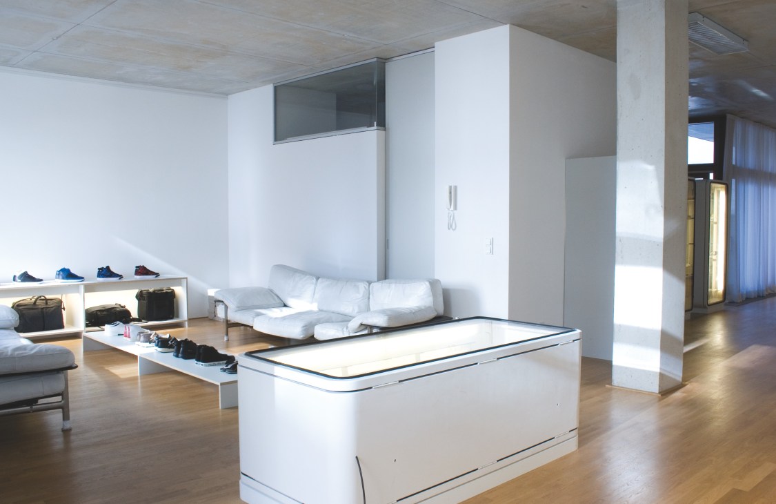 Interior of Firmament store in Berlin showing minimalist white display fixtures, cozy seating, and retail merchandise.