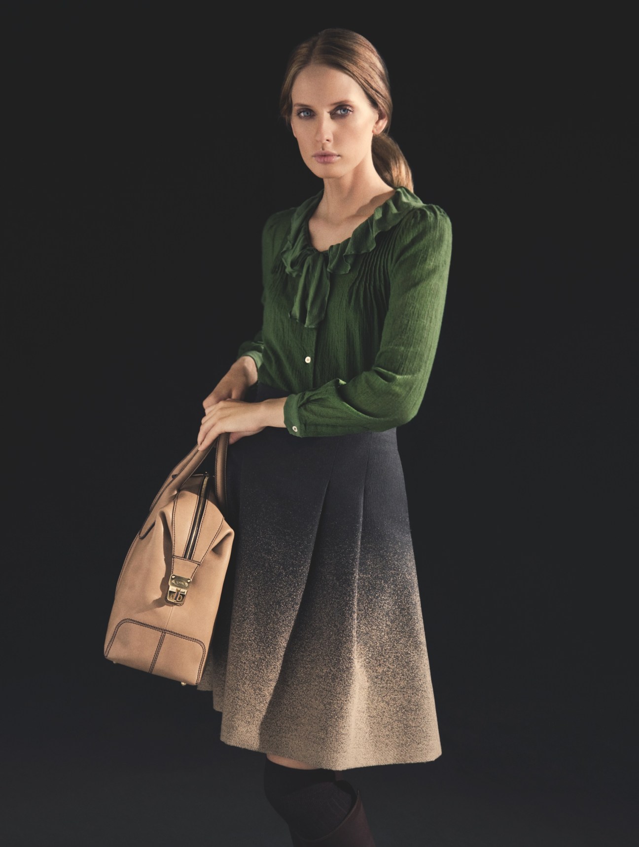 Woman wearing Aspesi shirt, Incotex skirt and Tod's bag against dark background