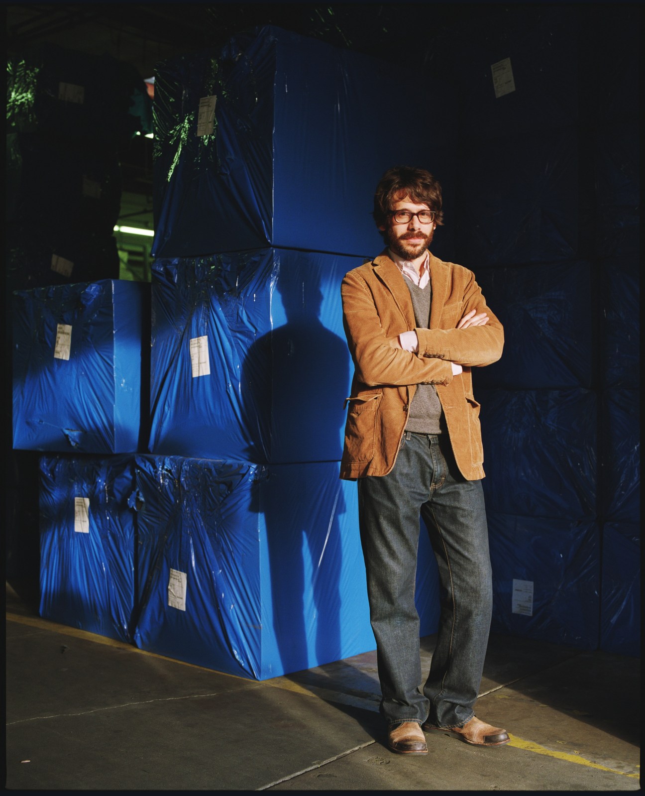 Jason Hoover, creative media manager, stands with arms crossed in front of stacked blue Pelican cases.