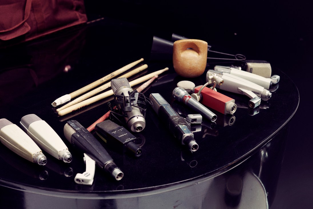 Collection of microphones and drumsticks arranged on a black surface.
