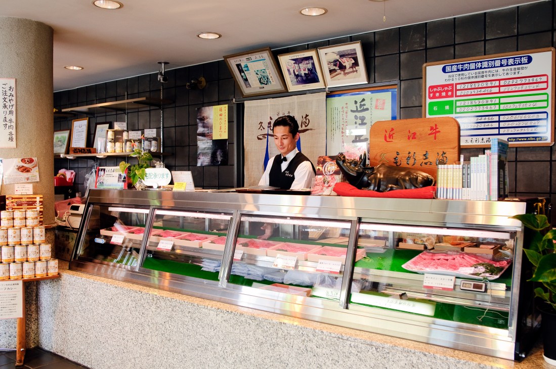 Omi beef displayed in refrigerated cases at Morishima restaurant counter with staff member behind counter.