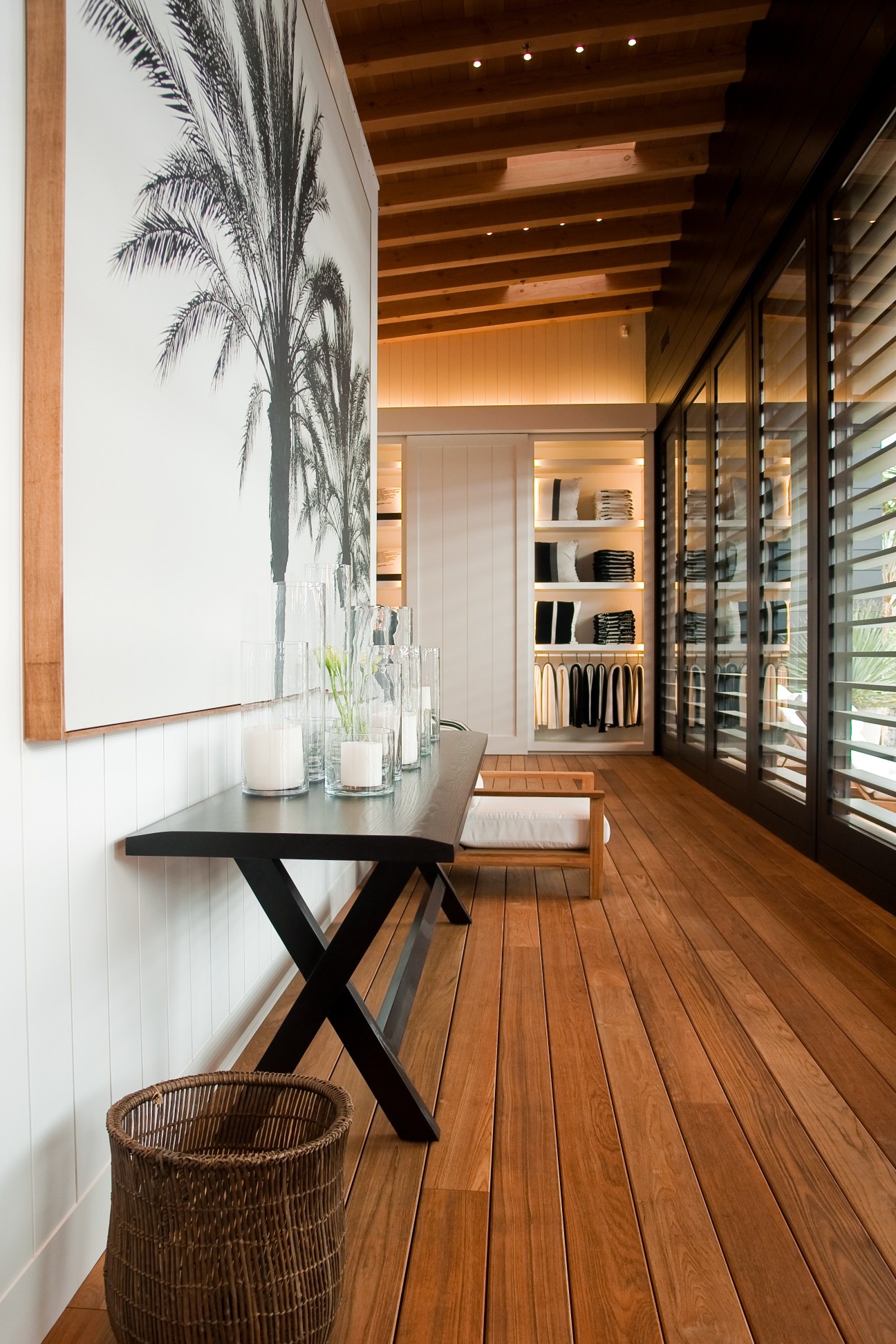 James Perse retail store interior with wooden flooring, palm artwork, display shelves and modern furnishings.
