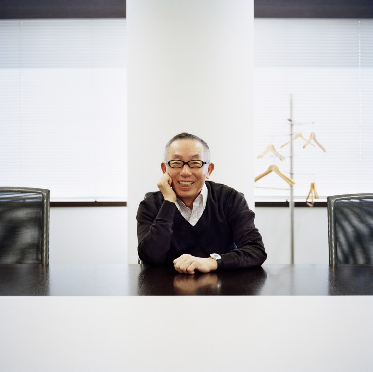 Tadashi Yanai, founder and president of Fast Retailing and Uniqlo, smiling at a conference table.