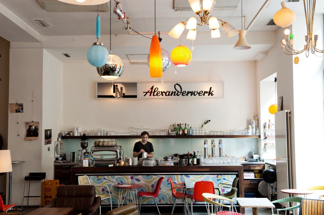 Interior of Phil café showing colorful pendant lights, barista counter, and contemporary furniture in Vienna.