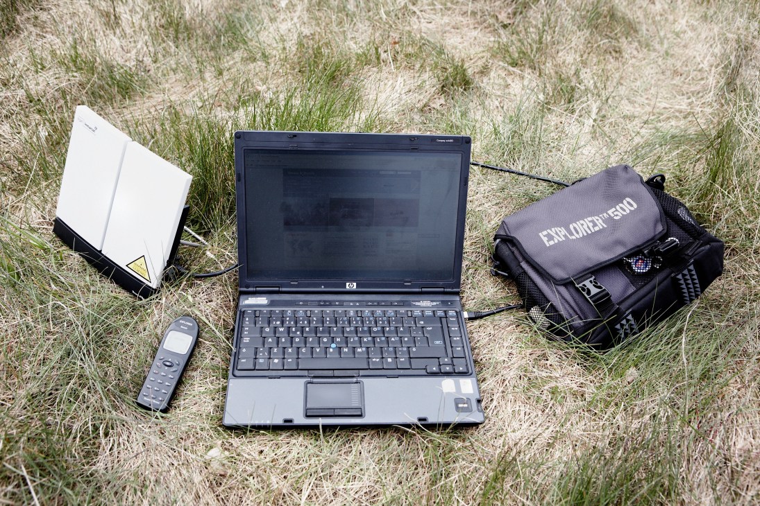Explorer 500 satellite communication kit displayed on grass with laptop, antenna, and carrying bag.