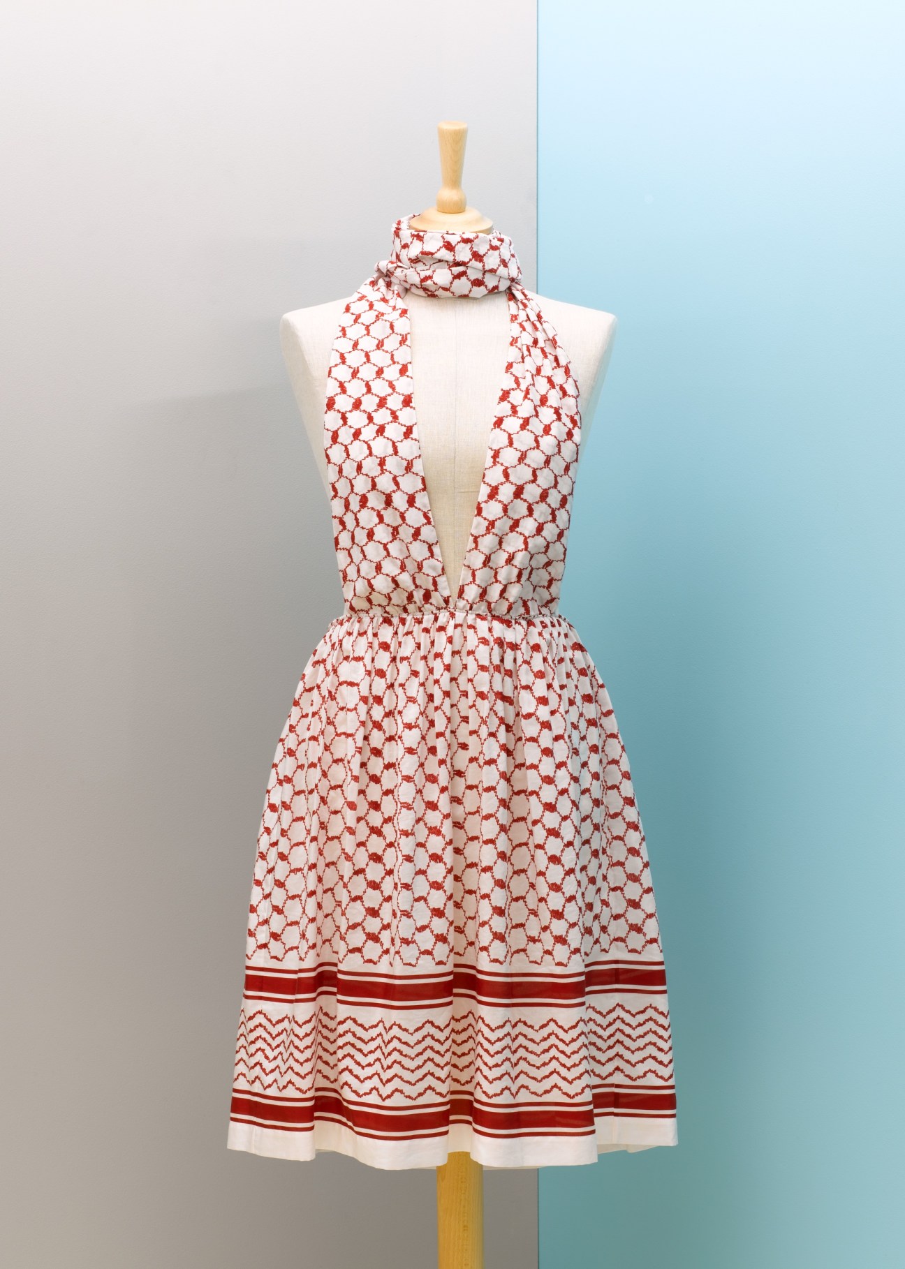 Red and white geometric patterned silk dress with Palestinian keffiyeh print on a dress form.
