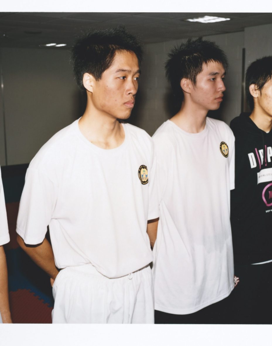 Macao taekwondo team members in white uniforms and black shirts stand together after training.