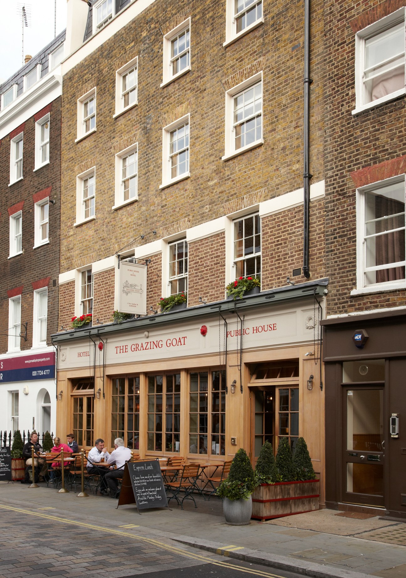 The Grazing Goat pub storefront with wooden facade, signage, and outdoor seating in central London.