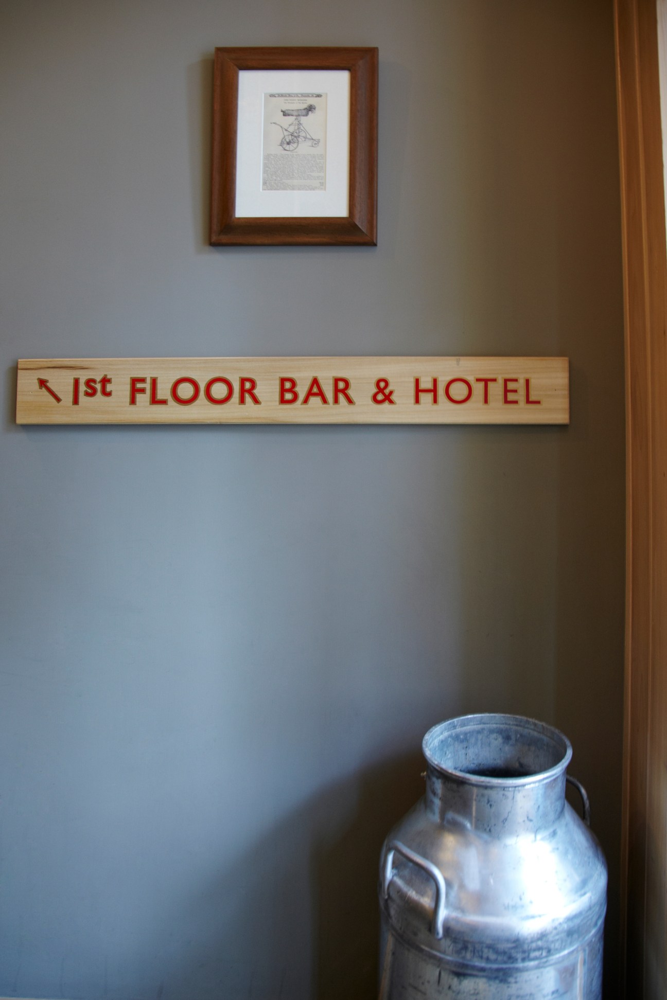 Interior signage reading '1st FLOOR BAR & HOTEL' above a metal milk churn