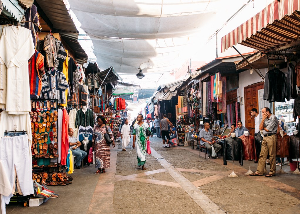 Covered market street in Rabat's medina with vendors selling colorful textiles and traditional goods.