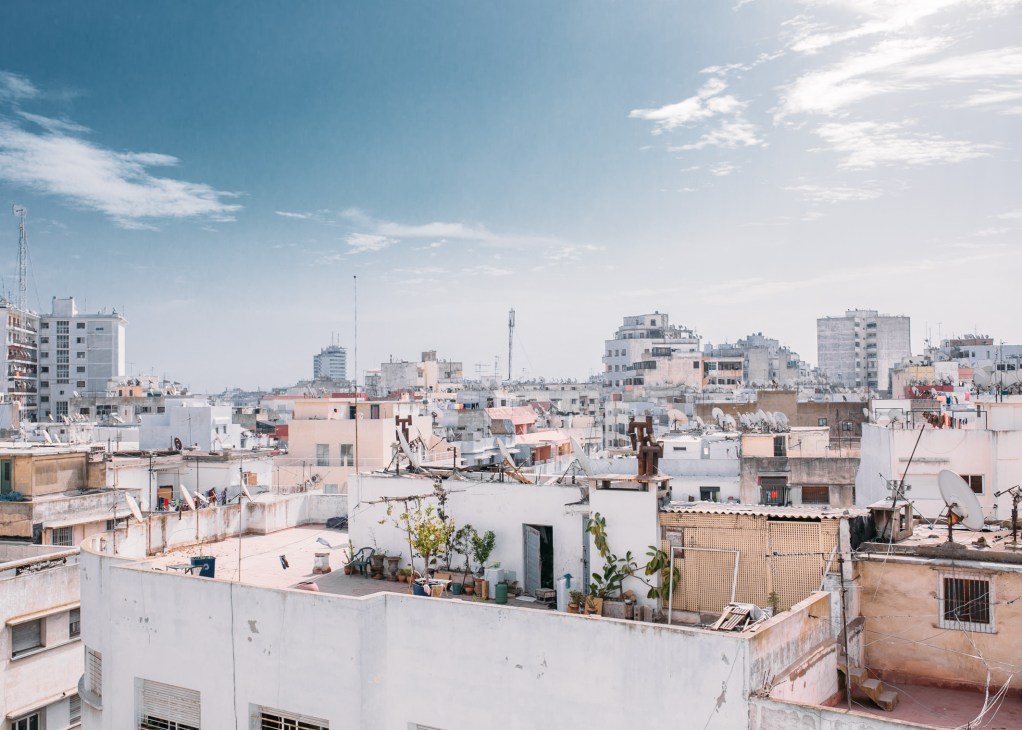 Aerial view of densely packed residential buildings in Casablanca with white and pink facades and rooftop structures.