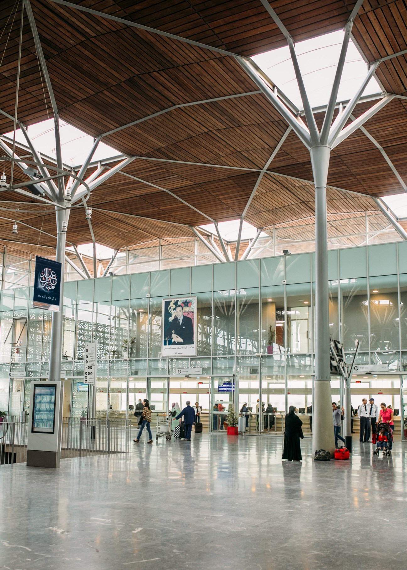 Modern railway station interior with wooden vaulted ceiling and steel support columns.