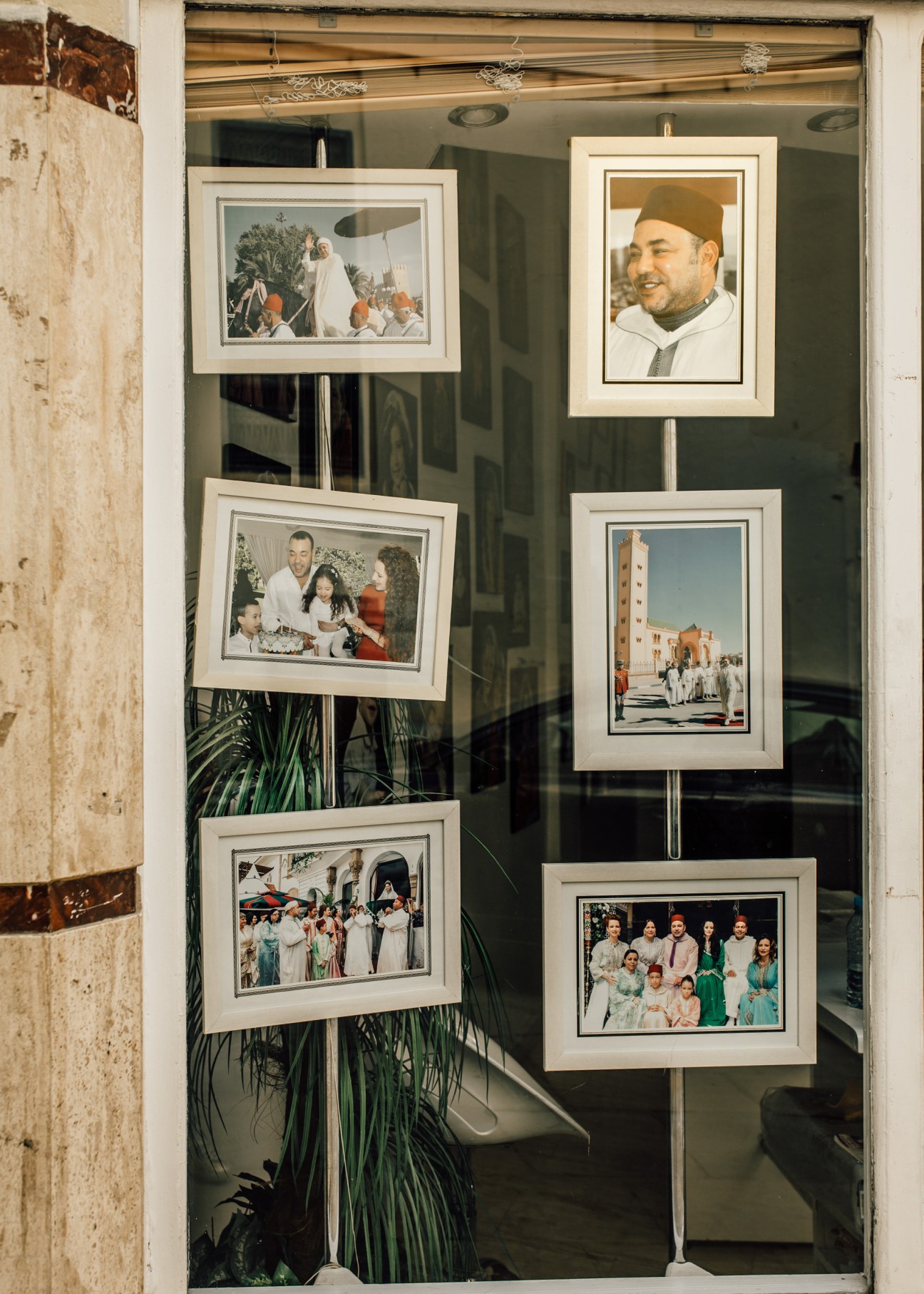 Multiple framed photographs of King Mohammed VI displayed in a shop window in Fes, Morocco.