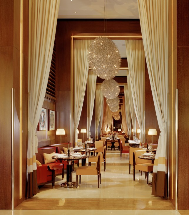 Elegant dining room at 45 Park Lane hotel with tall cream curtains, wooden accents, and hanging crystal chandeliers.