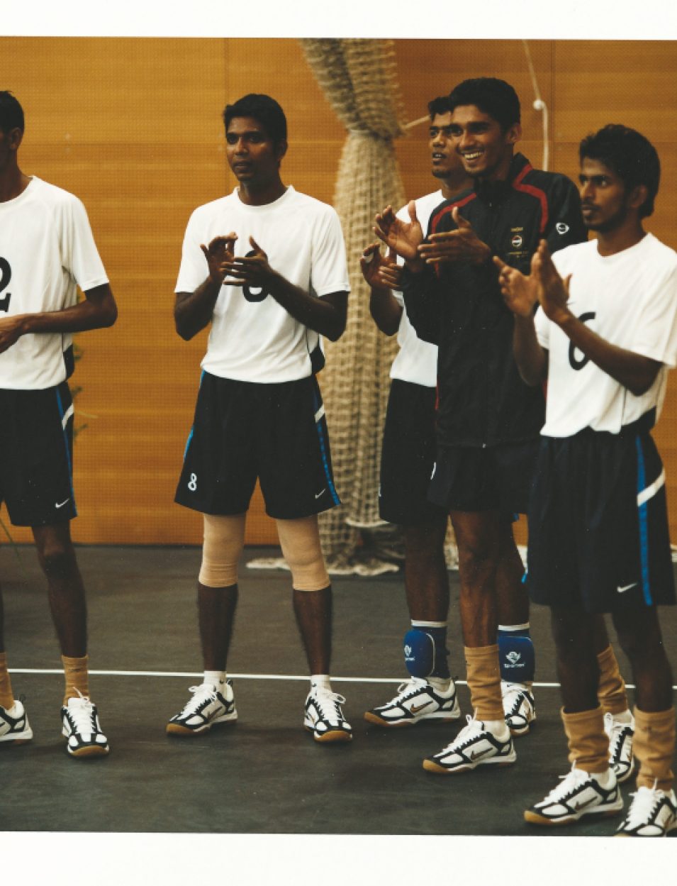 Indian women's volleyball team substitute players applauding from the sideline during competition.