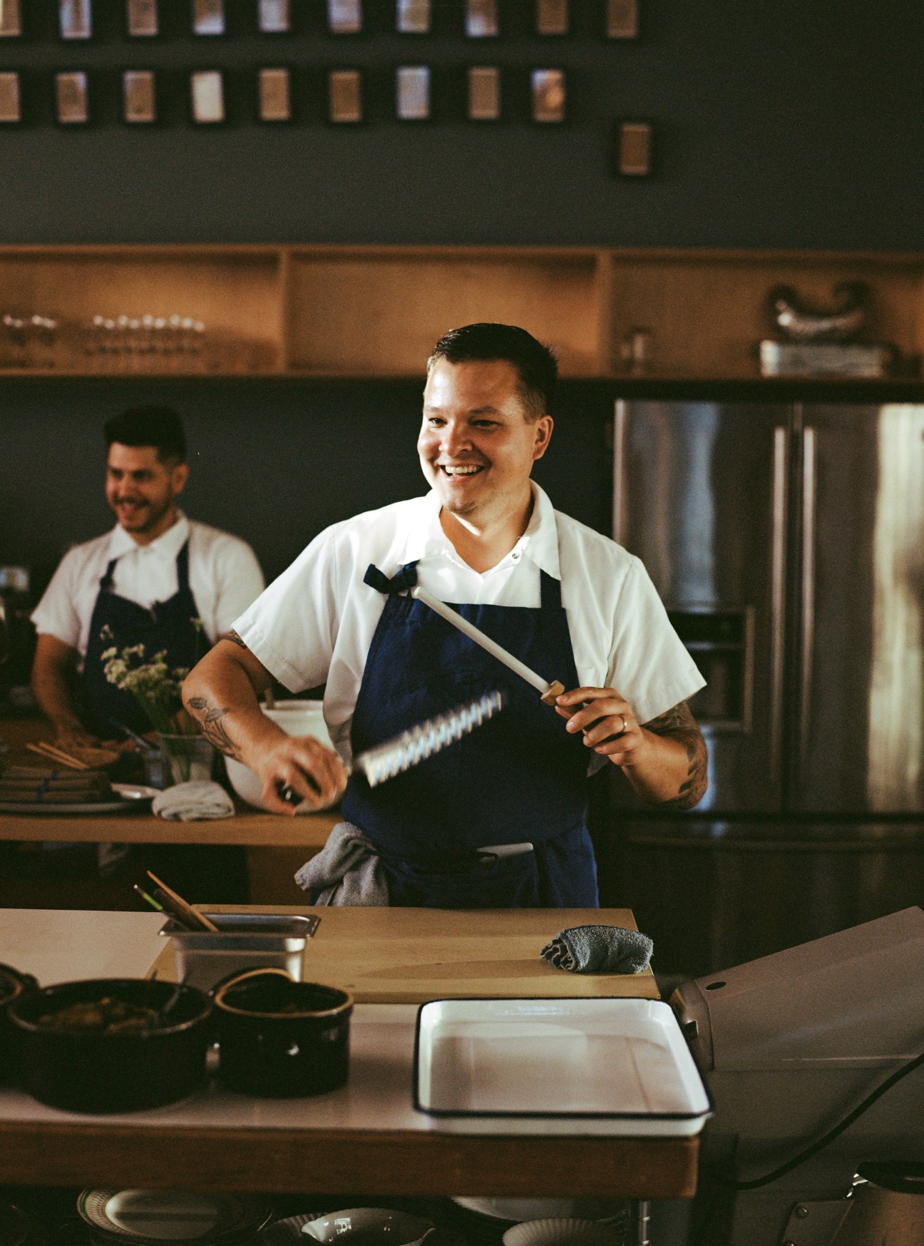 Chef Johnny Leach smiling while holding a knife in the kitchen at Stray Dogs restaurant.