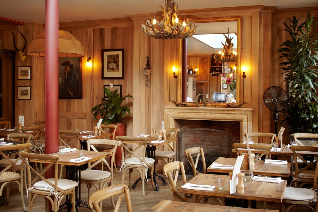 Interior of The Grazing Goat restaurant with wood paneling, fireplace, and dining tables set for service.