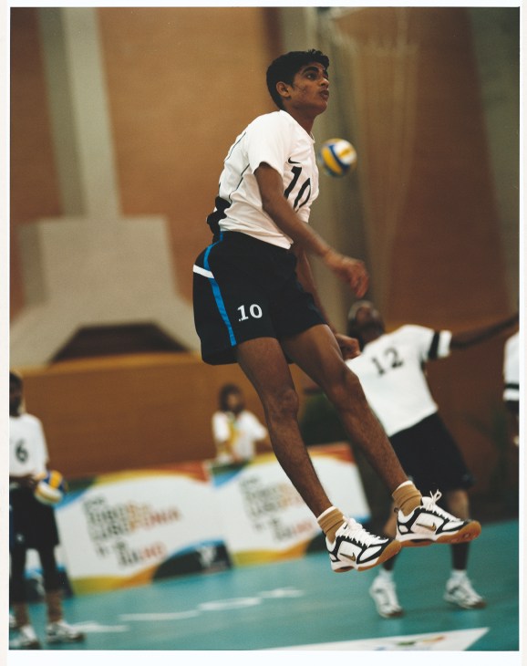 Indian male volleyball player wearing number 10 jersey jumps to hit the ball during indoor match.