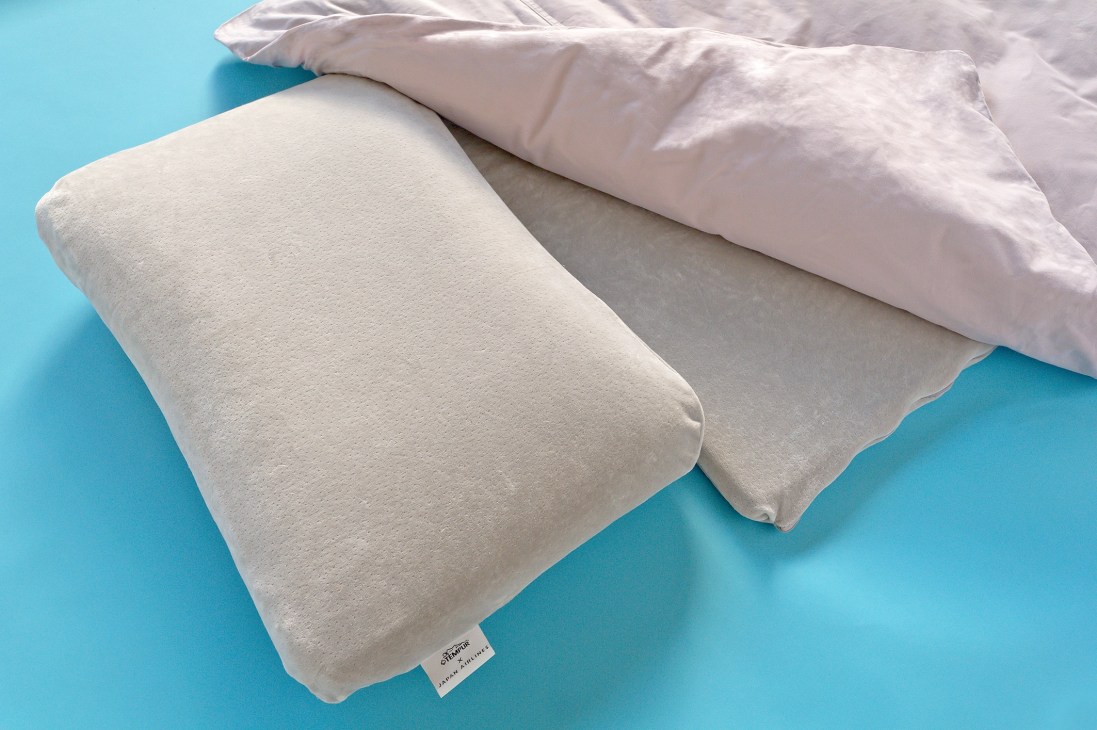White feather pillow and duvet on turquoise background, showing JAL first-class bedding quality.