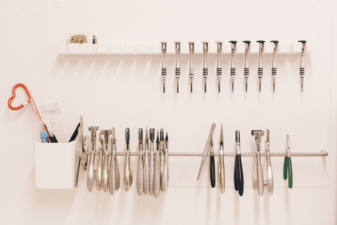 Wall-mounted display of custom handmade eyeglass frames and tools at Hartmann optician.