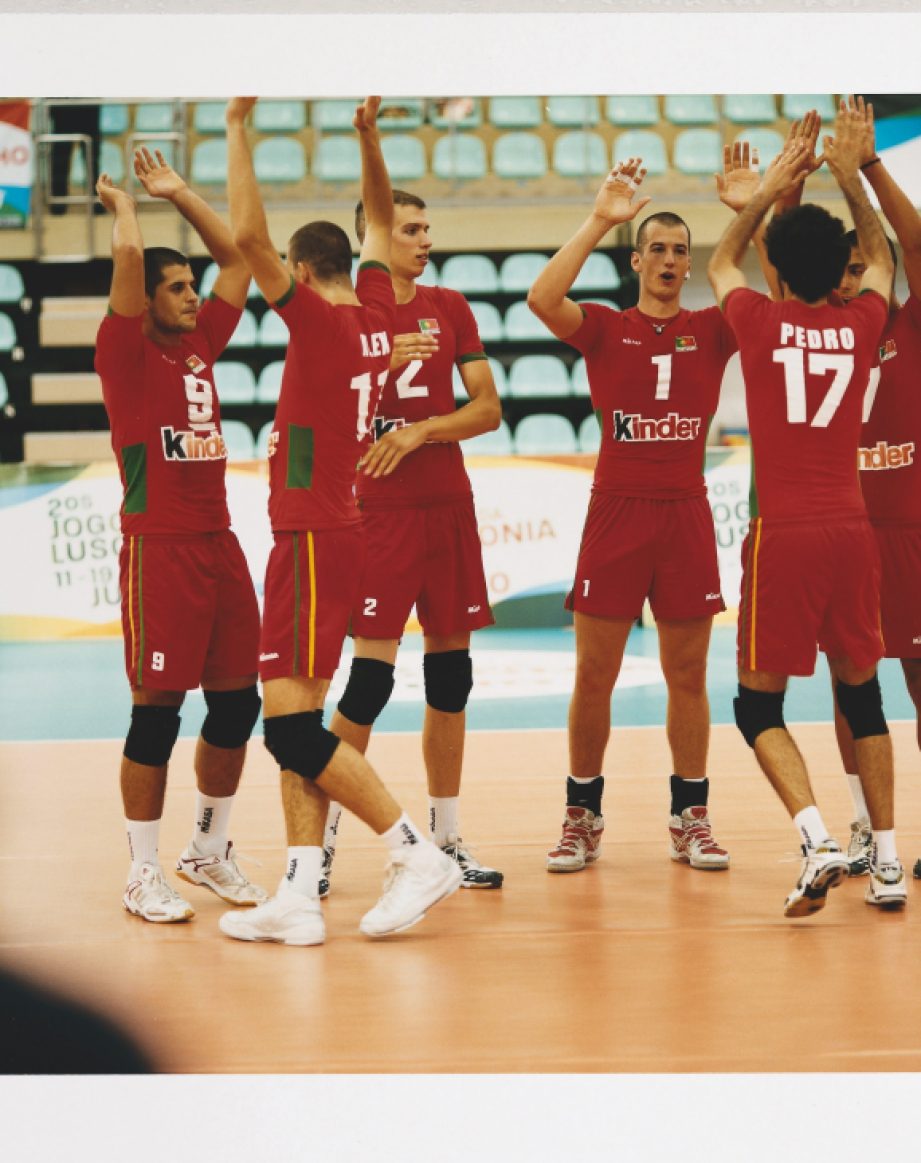 Portuguese volleyball team members in red uniforms celebrating during a match.