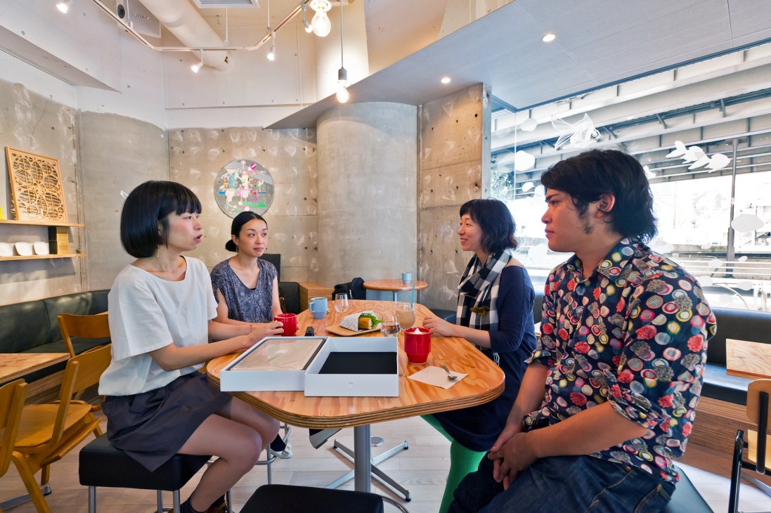 Four people gathered around a wooden table at FabCafe in Tokyo's Shibuya district.