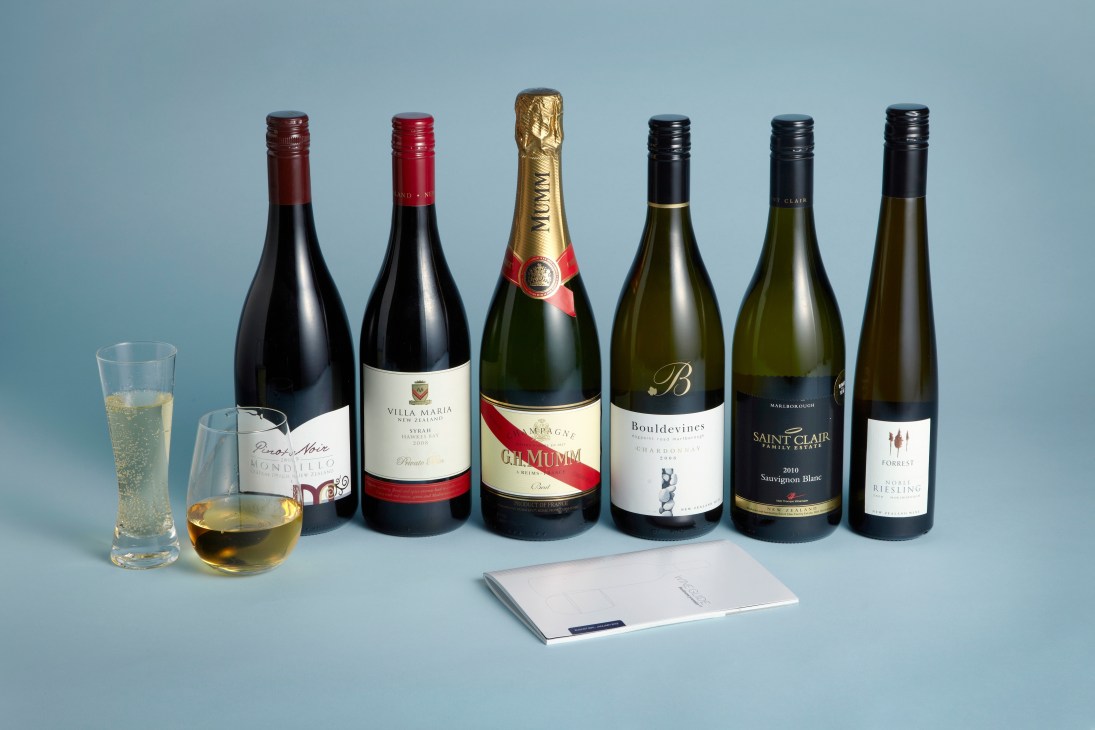 Selection of wine bottles including red, white, and champagne displayed with glasses and a wine list on blue background.
