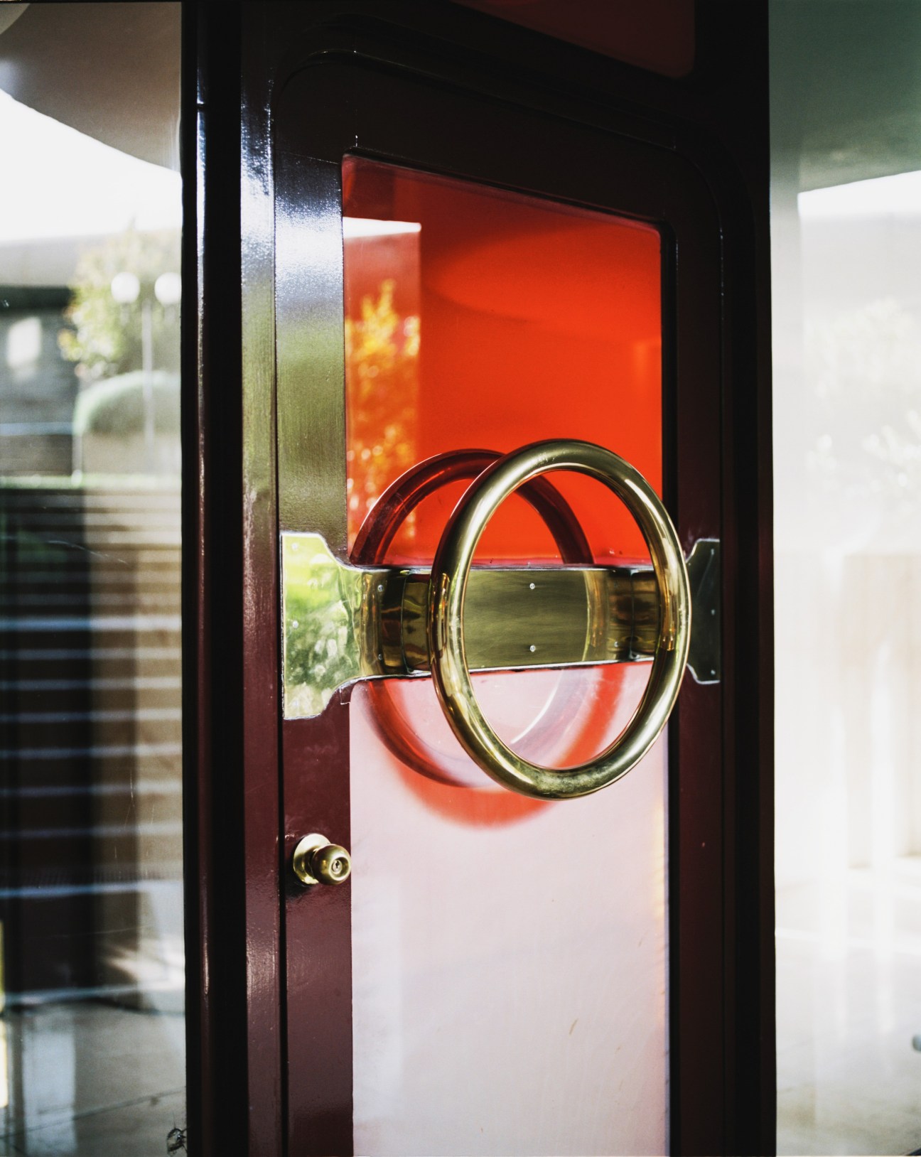 Brass door handle and red-painted door with textured glass panel in Torres Blancas building.