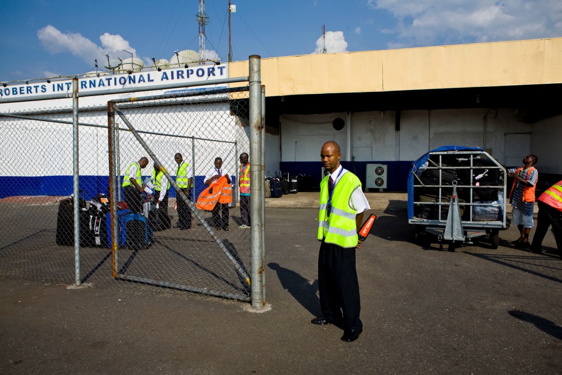Baggage handlers wearing high-visibility vests work on the tarmac at Roberts International Airport in Monrovia, Liberia.