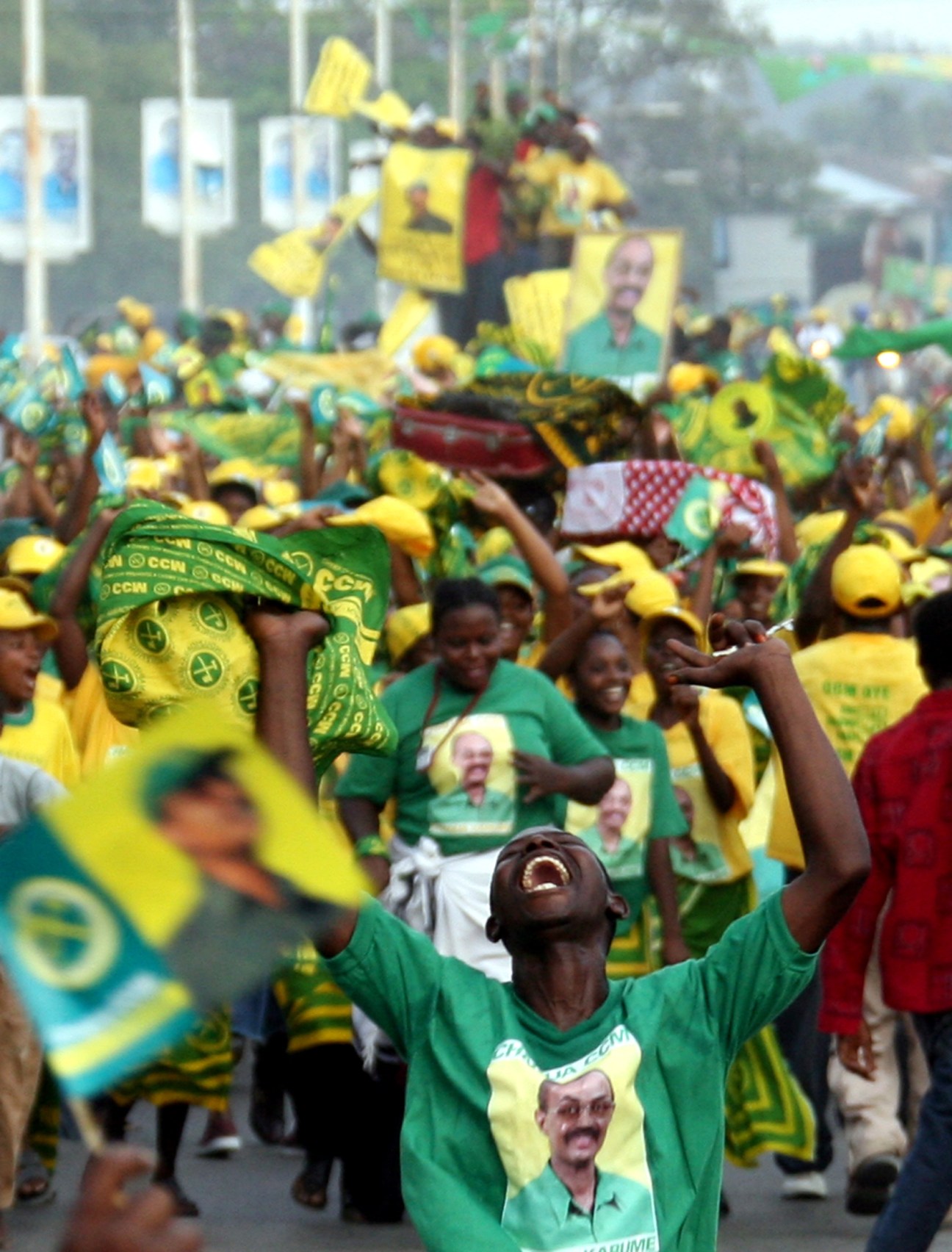 Supporters at a political rally in Zanzibar wearing yellow and green clothing and holding campaign signs.
