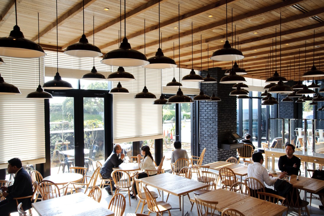 The Canteen café interior with black pendant lights, wooden beams, and diners at tables with Windsor chairs.