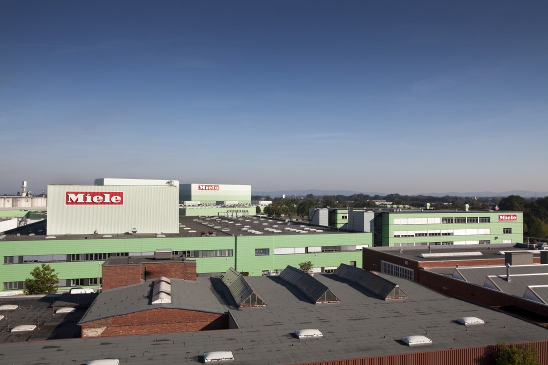 Aerial view of Miele's Gütersloh factory complex with green and white buildings branded with the Miele logo.