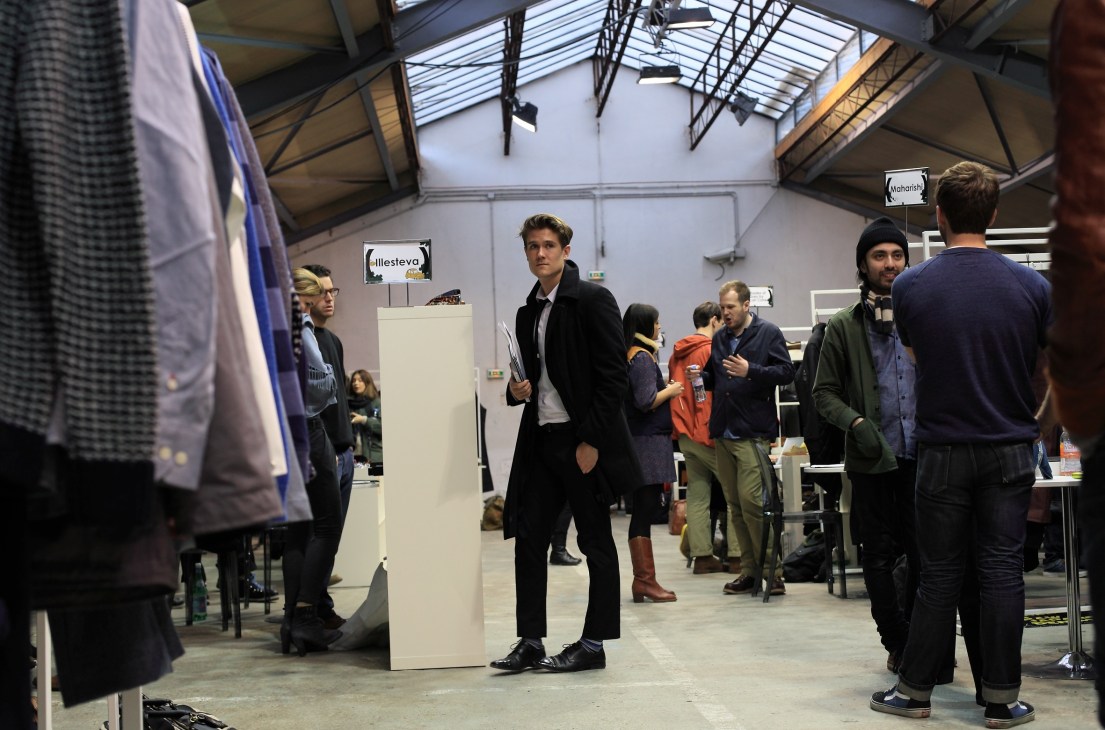Visitors browsing fashion brand displays at Capsule trade fair in a converted car park venue.