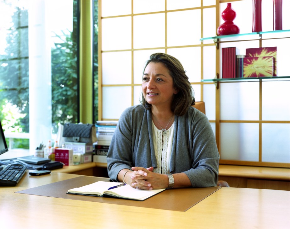 Isabelle Herbreteau, Clarins president, seated at her desk in a modern office with shelving behind her.