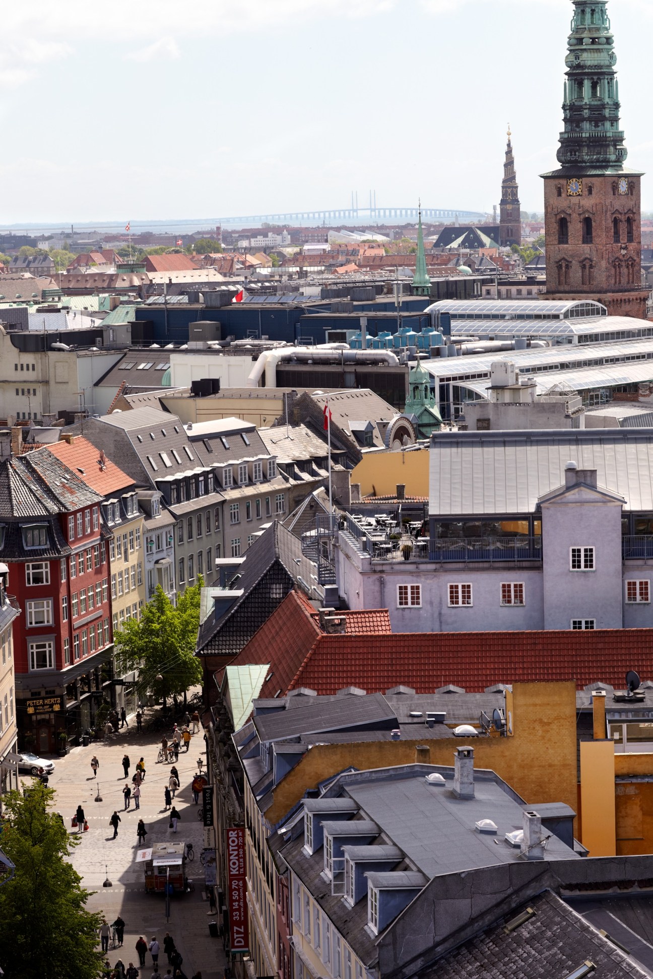 Aerial view of Copenhagen showing historic buildings, church spire, and Øresund Bridge in background