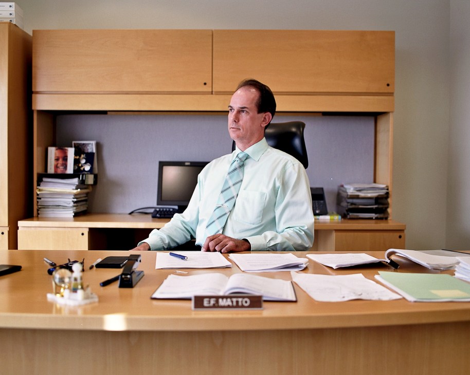 Eric Matto, deputy director of the national bank, sits at his desk in an office.
