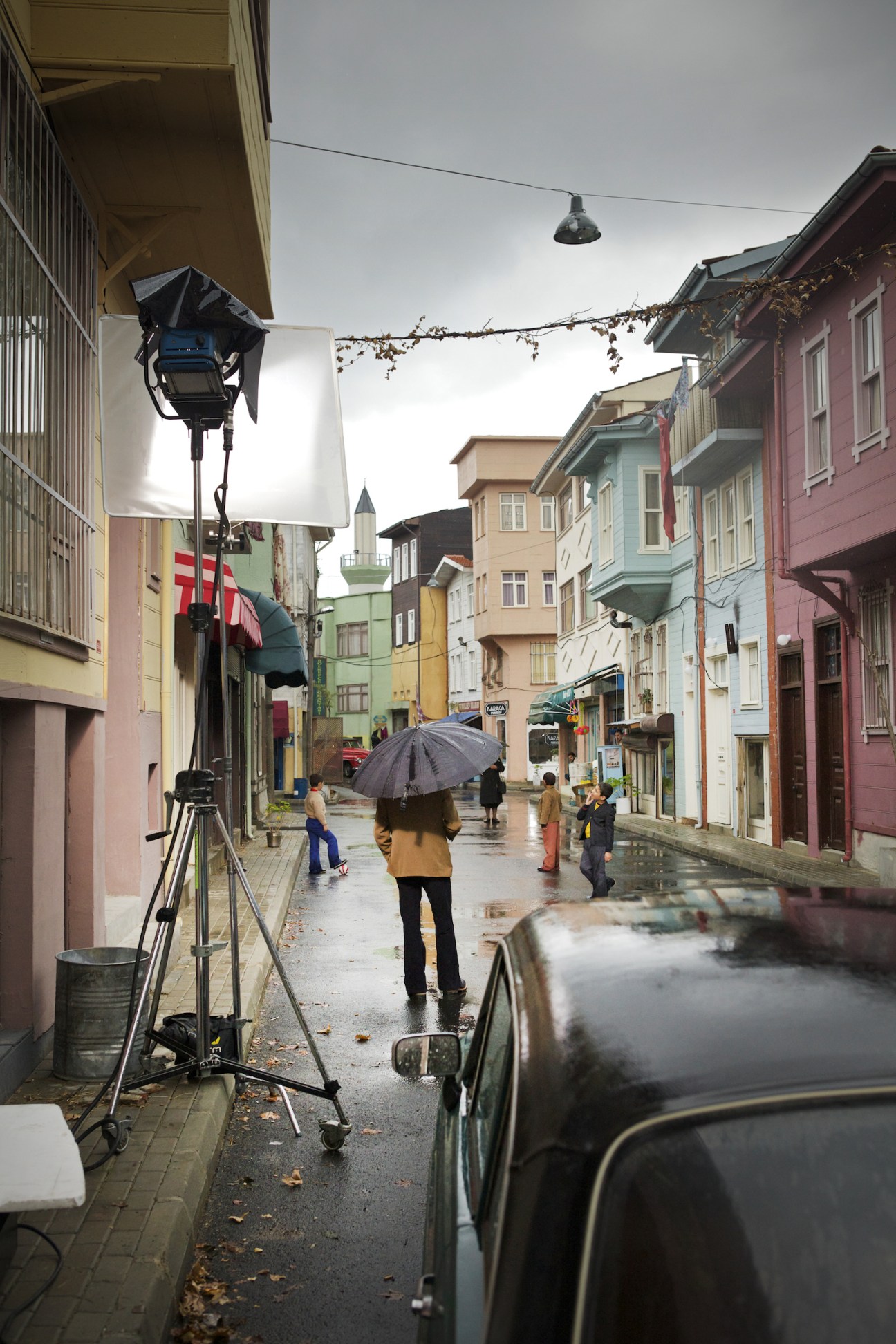 Film crew with lighting equipment filming on a colorful Istanbul street during production of Turkish drama series Öyle Bir Geçer Zaman Ki.