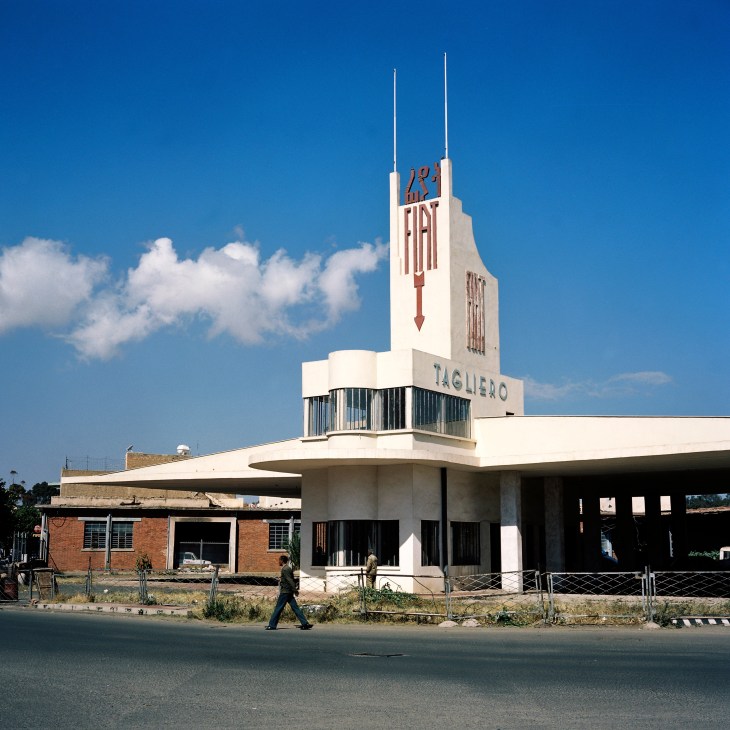 Art Deco building with Fiat signage and tower in Asmara, Eritrea under blue sky.