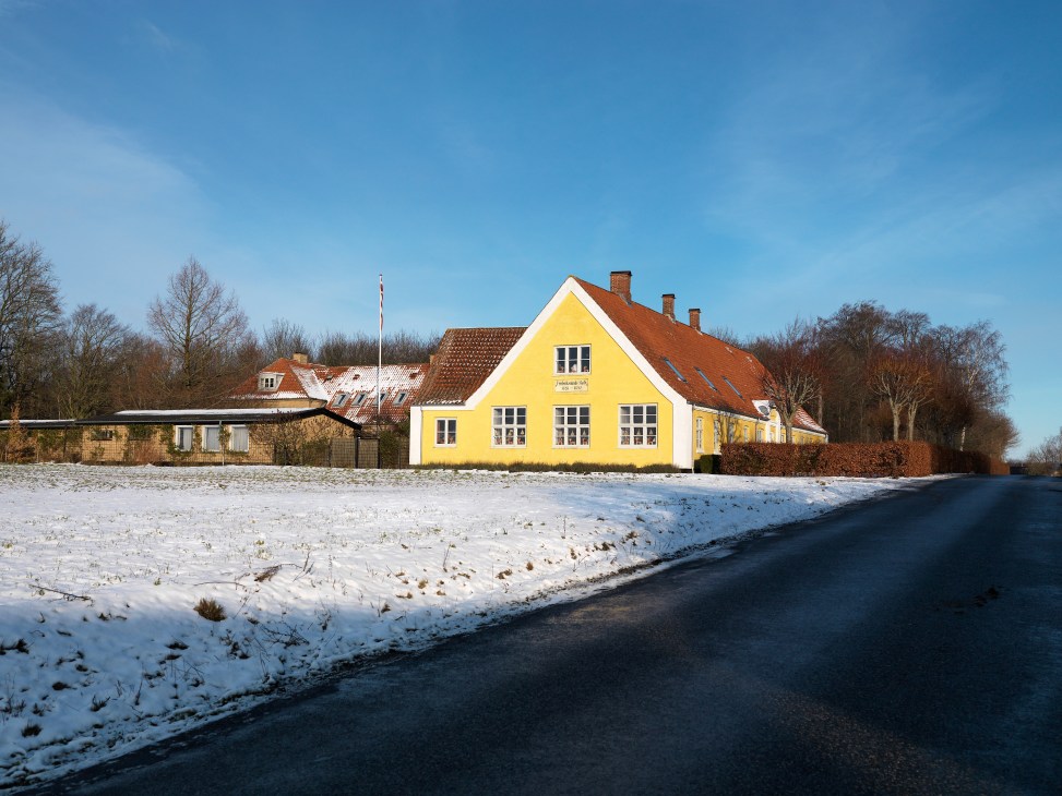 Yellow cottage with red roof in snowy Danish landscape, Flensted Mobiles showroom and family home.