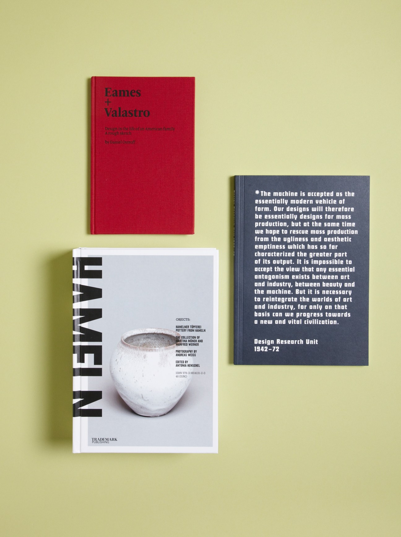 Three design books displayed on a pale yellow background: a red Eames + Valastro book, a white Hameln pottery book, and a dark blue Design Research Unit book.