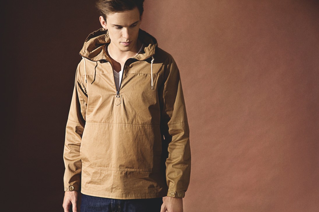 Man wearing a beige hooded cotton jacket with silk-lined sleeves against a brown background