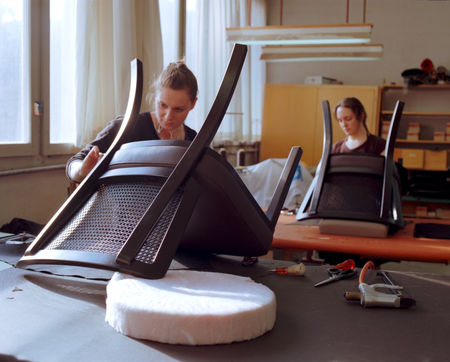 Woman working on upholstering a chair seat in the Horgenglarus factory upholstery department.