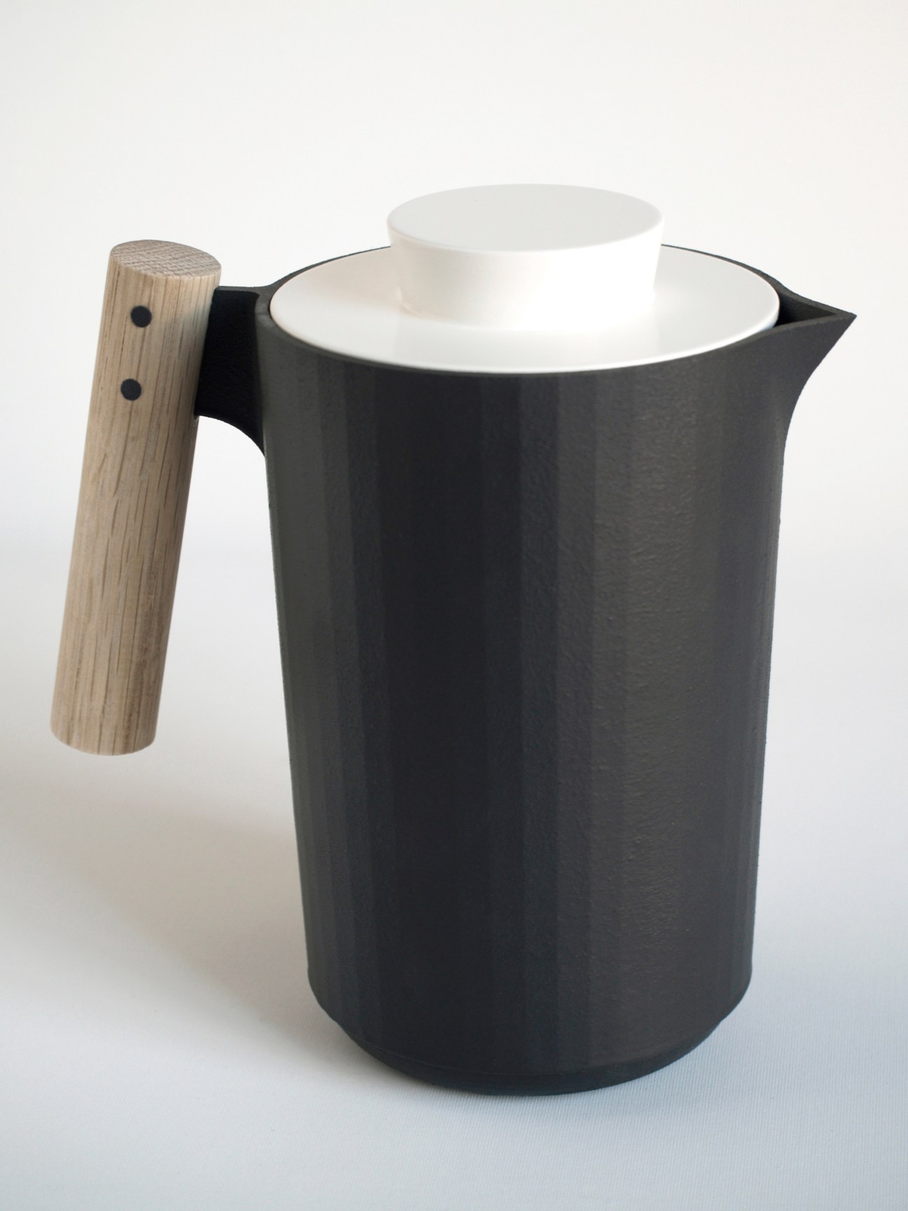 Black cast-iron kettle with wooden handle and white interior ceramic lining.