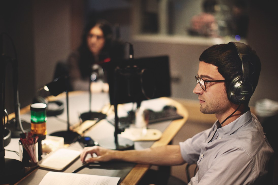 Jonathan Openshaw wearing headphones at a radio studio desk with microphone and equipment.