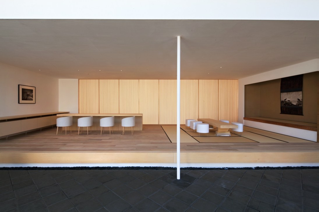 Modern minimalist interior with wooden flooring, white column, and wooden slat wall panels.