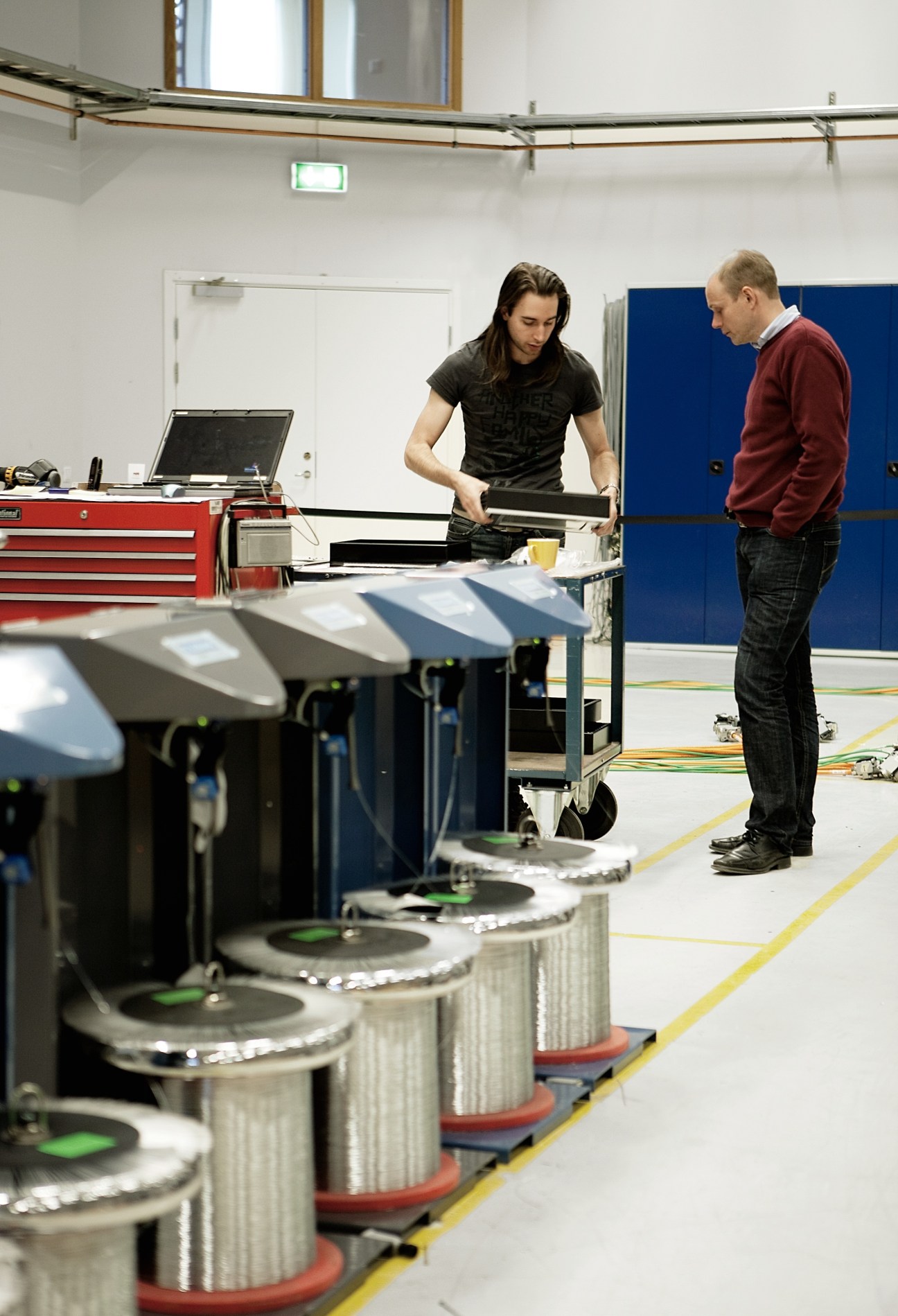 Two Tolerans employees work with industrial stitching machinery in a factory setting.