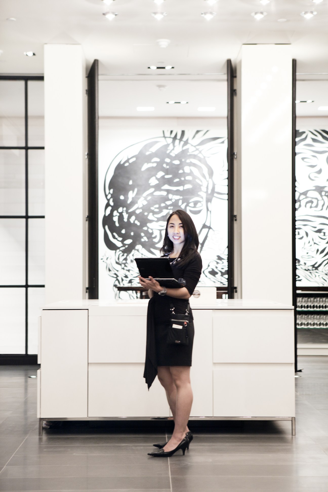 Woman in black dress holding tablet standing before Nick Hornby sculpture in Andaz Fifth Avenue lobby
