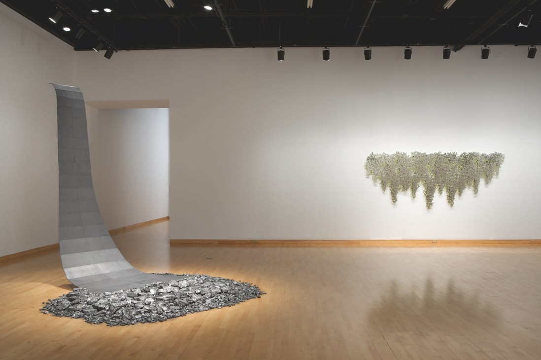 Gallery installation featuring Teresita Fernández's 'Drawn Waters (Borrowdale)' with graphite sculpture and cascading material on wooden floor.