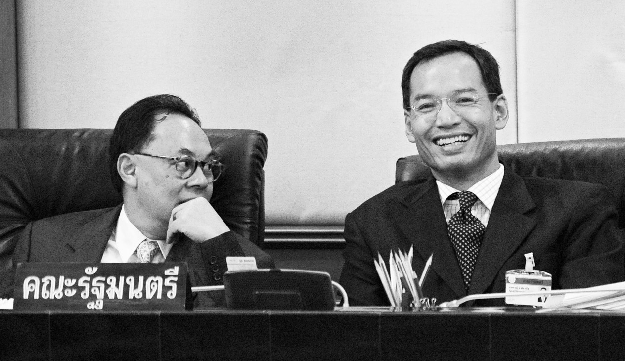 Korn Chatikavanij smiling at an official meeting alongside another man in business attire.